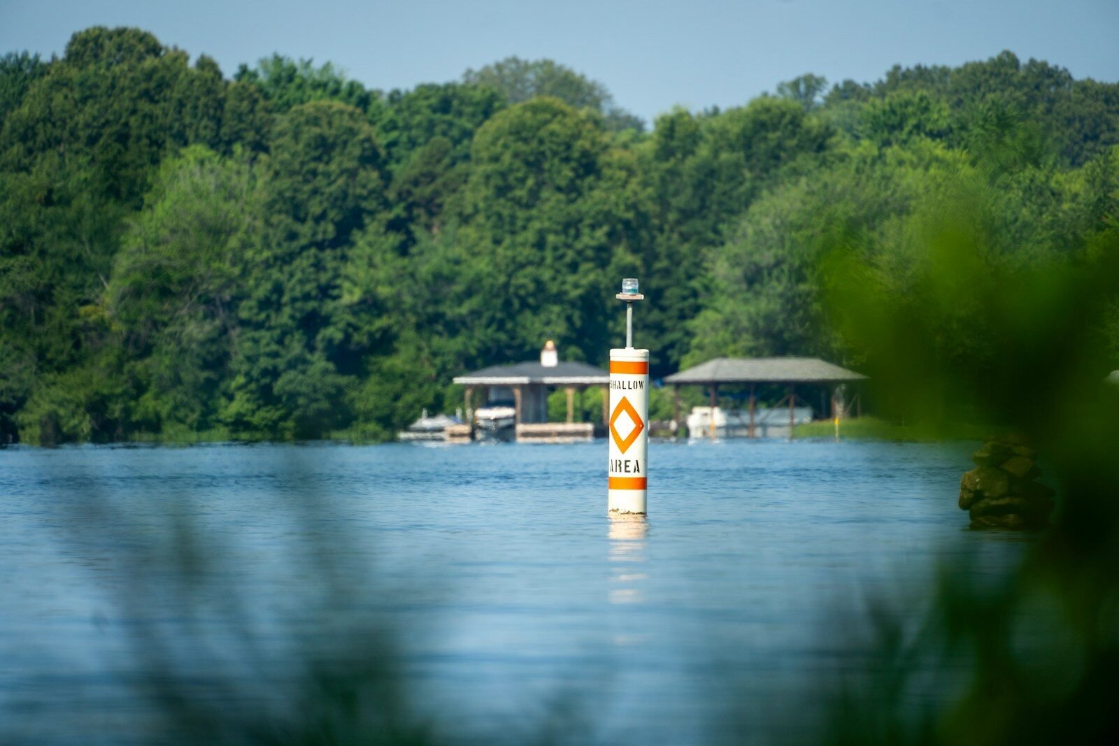 A buoy floats near green trees and buildings.